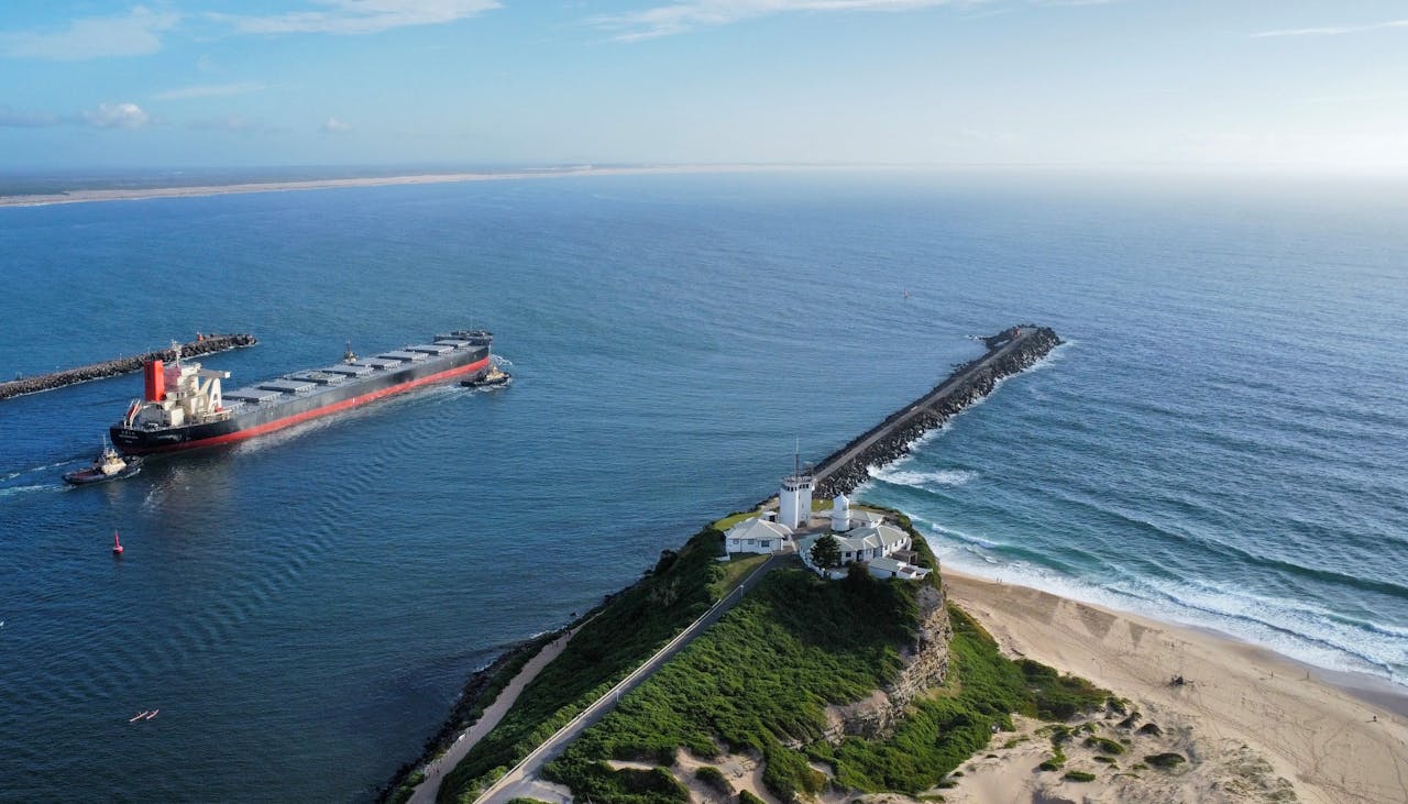 The Art of Drawing Readers In: Your attractive post title goes here Aerial view of Nobbys Lighthouse overlooking a coal ship entering Newcastle Harbour on a clear day.